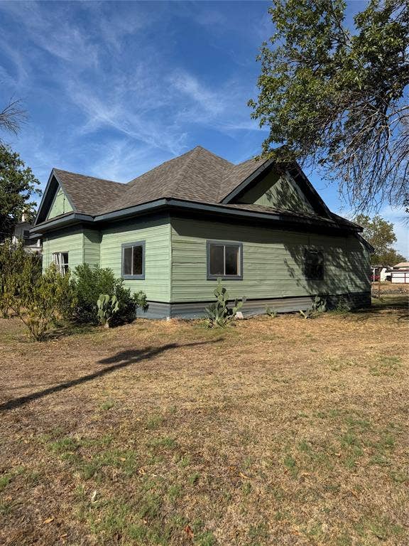 102 N 6th Street W, Dawson, TX 76639 Pitched shingle roof with dark trim, green horizontal siding, and multiple windows