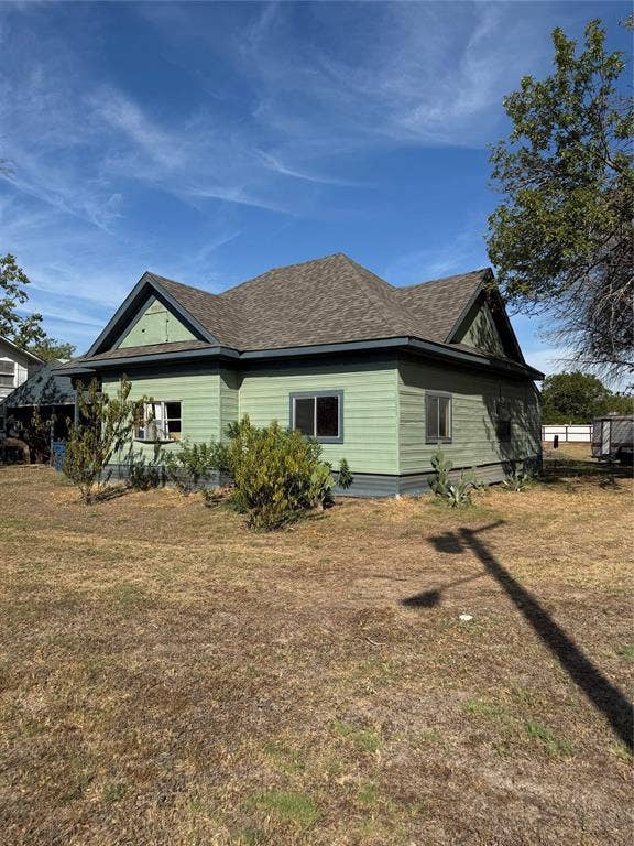 102 N 6th Street W, Dawson, TX 76639 Gable roofline with asphalt shingles, light green horizontal siding, dark trim, and multiple windows