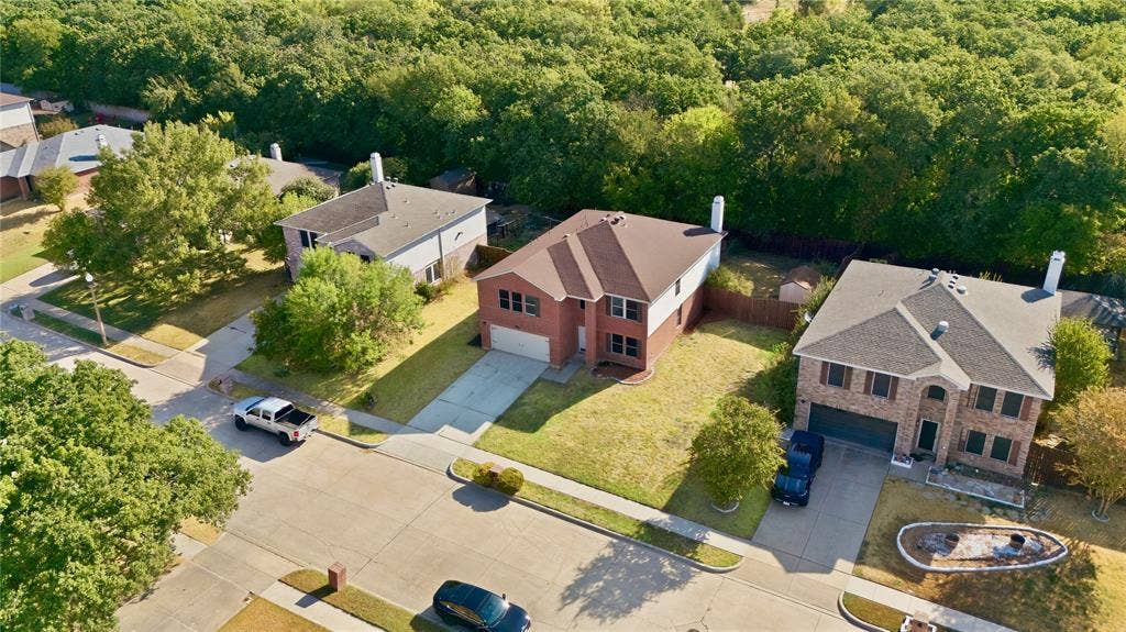 Traditional brick-front residence with a two-car garage, concrete driveway, and mature landscaping