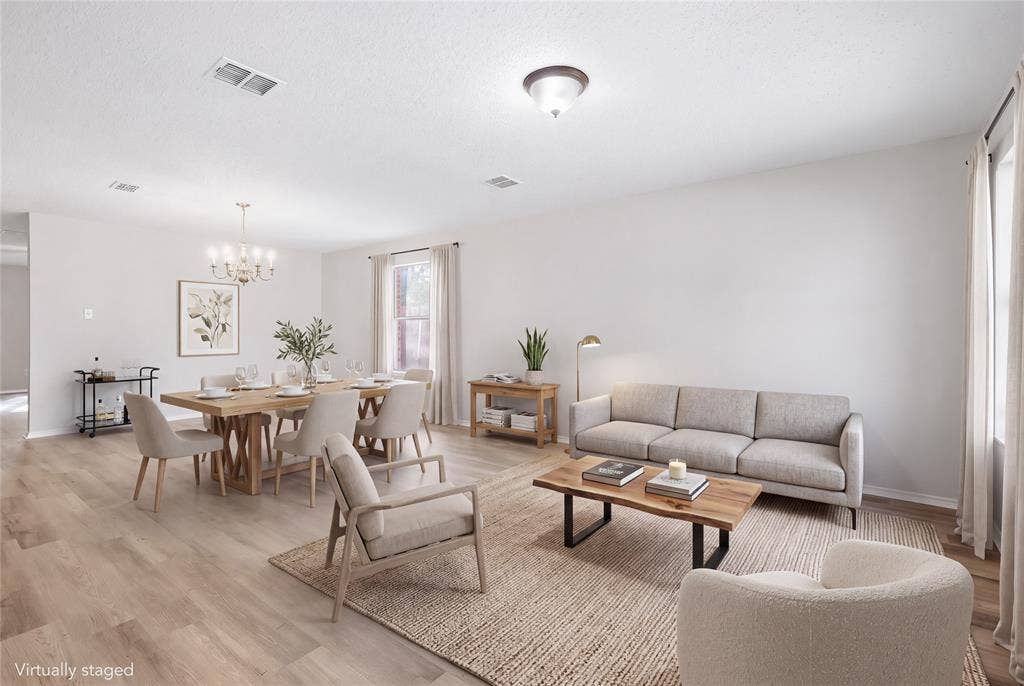 Open-concept living space featuring wood-finish flooring, recessed lighting, and a prominent window with drapes