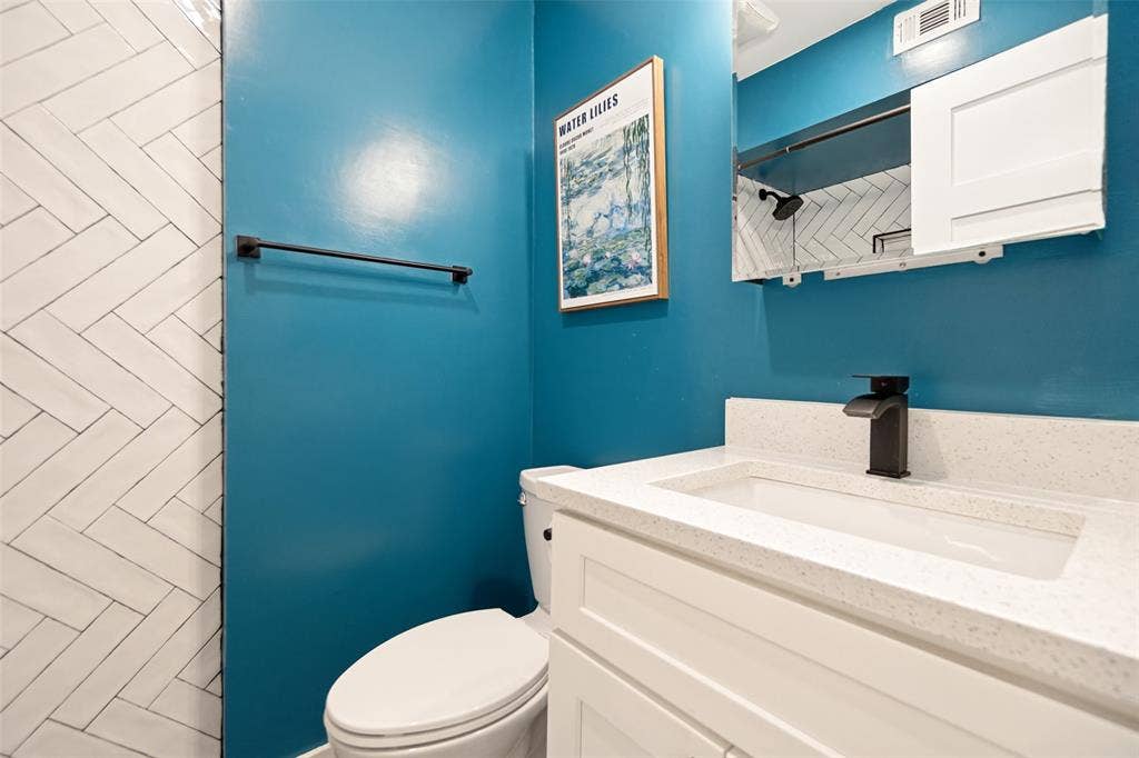 9038 Flicker Lane, Dallas, TX 75238 Vanity with an integrated rectangular sink, white countertop, white shaker-style cabinetry, and a matte black faucet