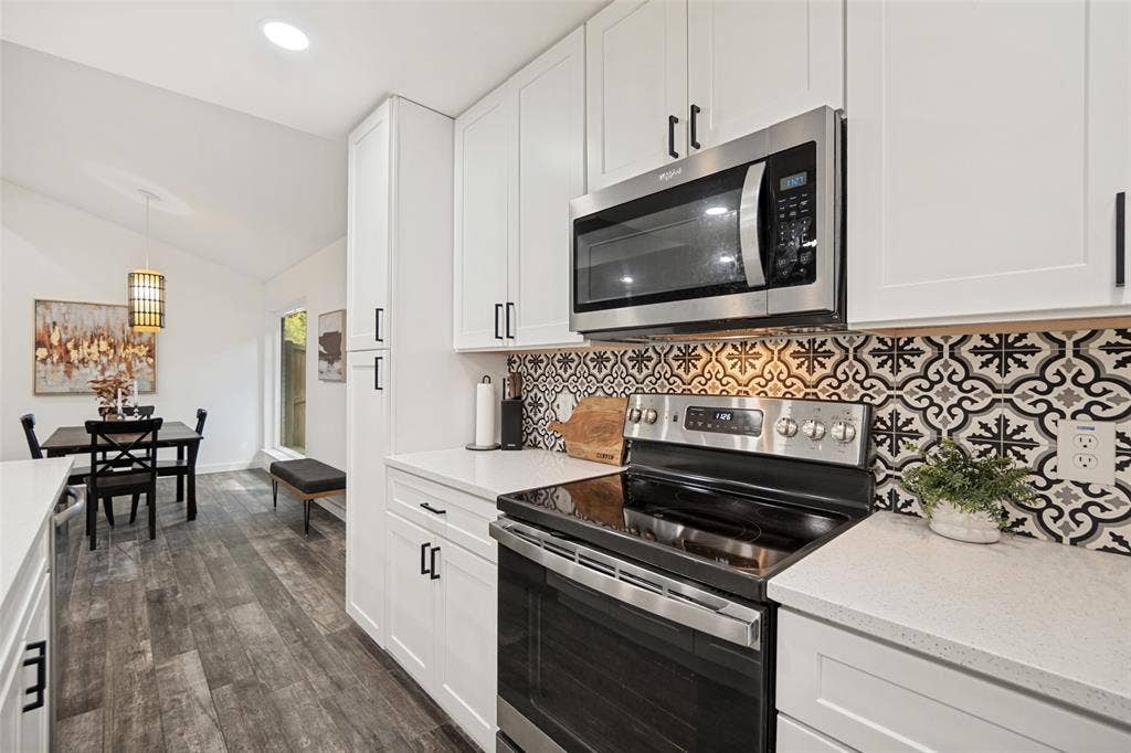 9038 Flicker Lane, Dallas, TX 75238 Modern kitchen featuring white shaker cabinetry, stainless steel appliances, patterned tile backsplash, and light-colored countertops