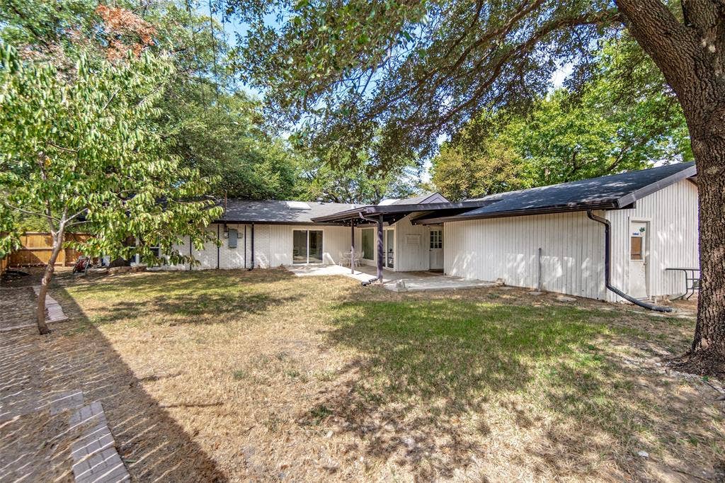 9038 Flicker Lane, Dallas, TX 75238 Expansive backyard with mature trees, a concrete patio, and a privacy fence