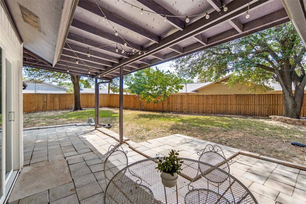 9038 Flicker Lane, Dallas, TX 75238 Covered patio featuring a paved surface, direct backyard access, and string lighting