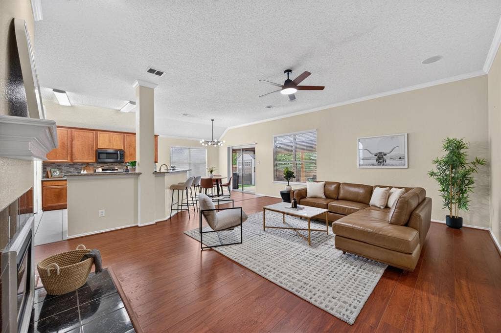Open-concept interior featuring wood-finish flooring, vaulted ceilings, a fireplace with a black tile hearth, and sliding glass patio doors