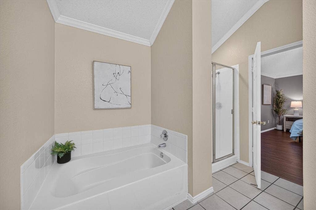 Bathroom featuring a vaulted ceiling, a built-in soaking tub with tile surround, and a walk-in shower with a framed glass door