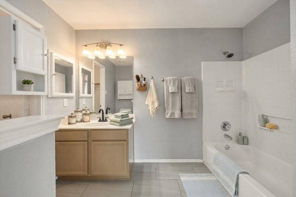 Dual vanity with individual framed mirrors, light wood-finish cabinetry, and matte black plumbing fixtures