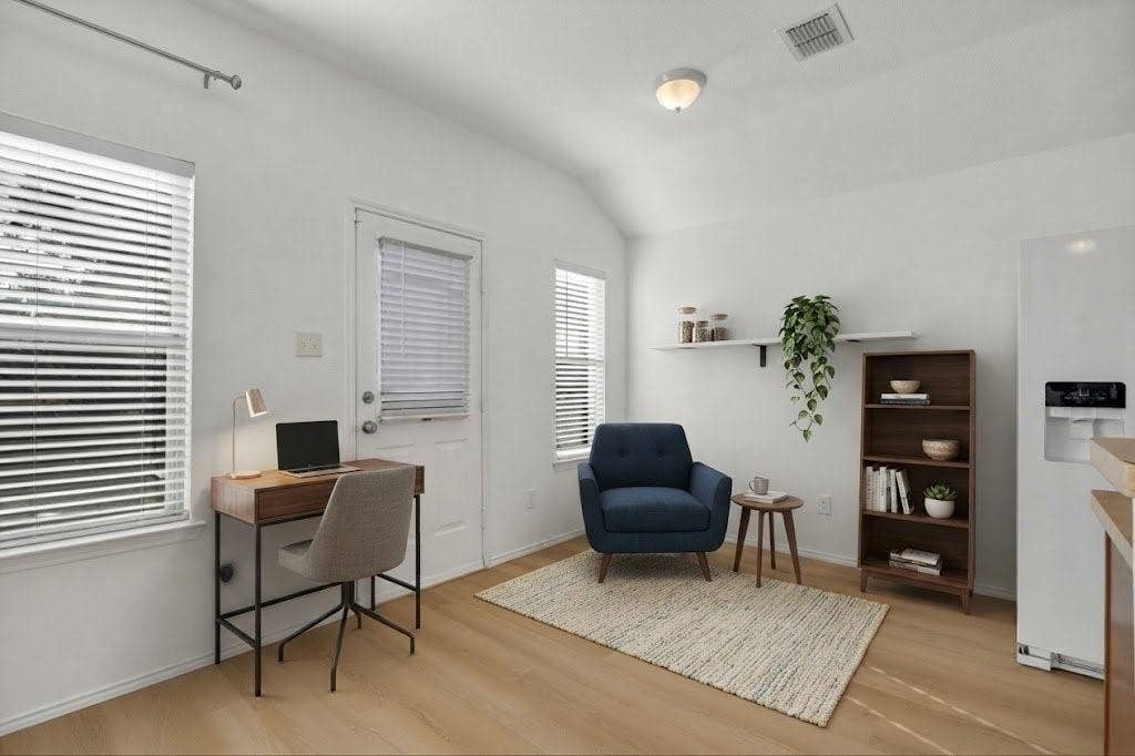 Light wood-finish flooring, white walls, and multiple windows with blinds