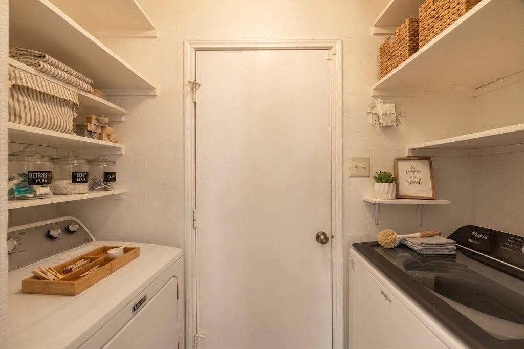 Integrated laundry area with built-in shelving, a white washer, and a black top-loading dryer