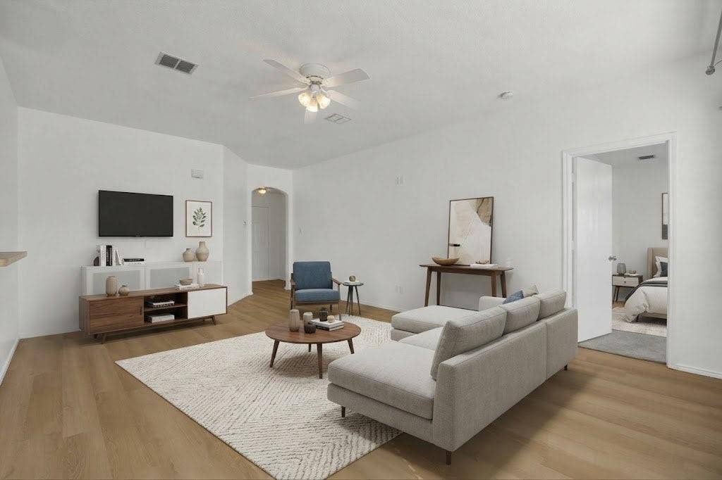Wood-finish flooring throughout, white painted walls, and a ceiling fan with integrated lighting