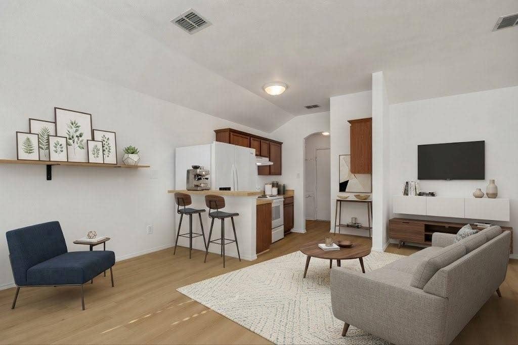 Open-concept living area with wood-finish flooring, vaulted ceiling, and recessed lighting