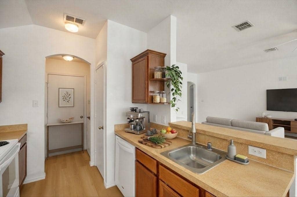 Kitchen with wood-finish flooring, wood cabinetry, and a stainless steel sink