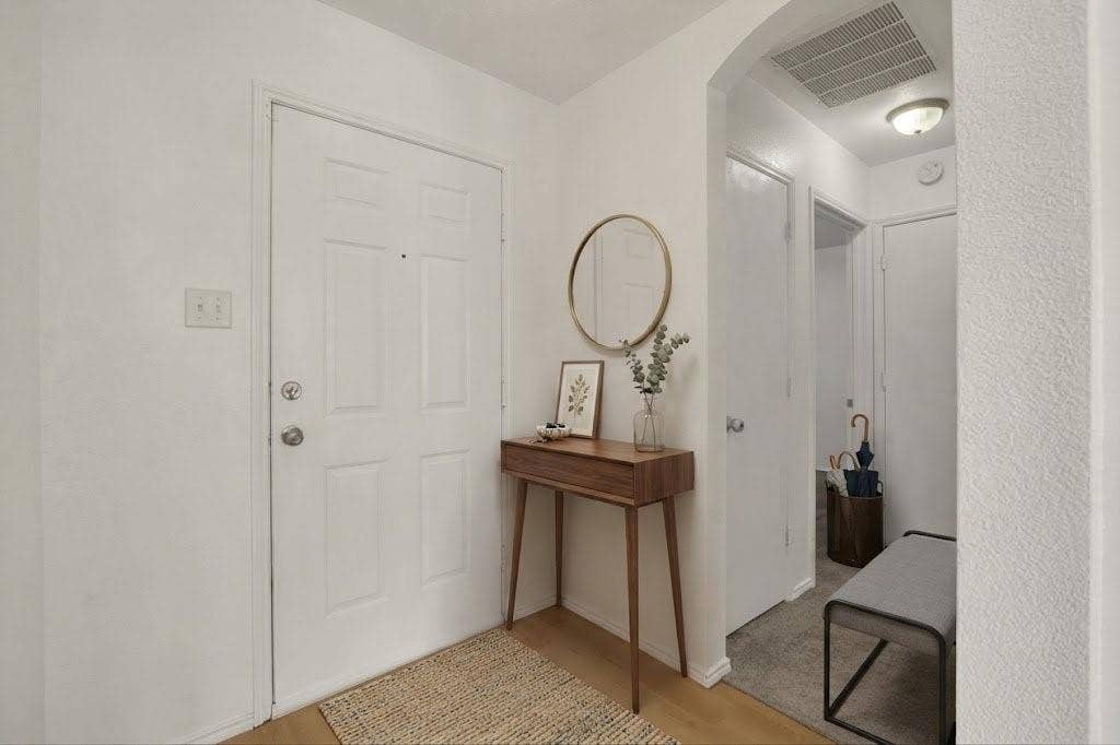 Light wood-finish flooring with a white paneled door and archway