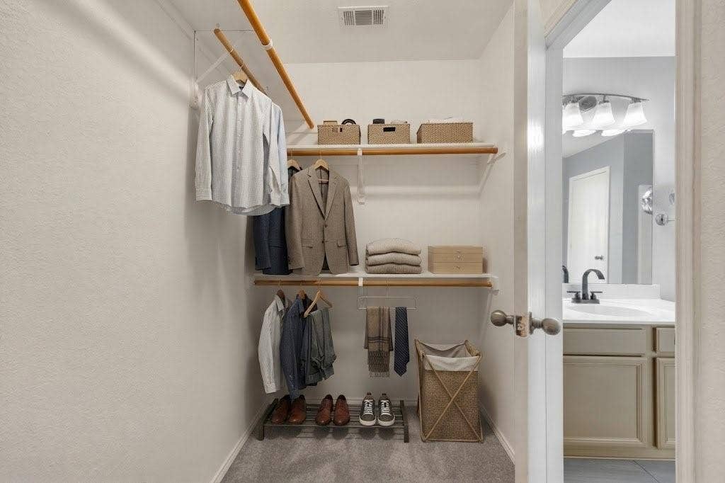 Built-in closet shelving, double hanging rods, and gray carpeting