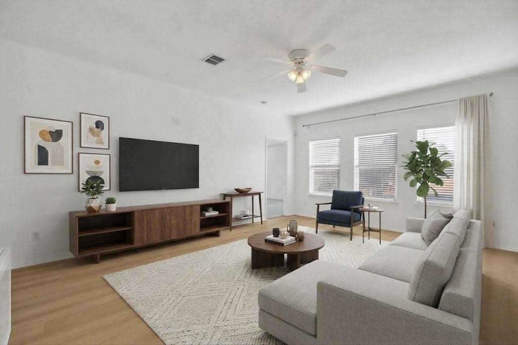 Wood-finish flooring, white walls, multiple windows with blinds, and a ceiling fan with integrated lighting