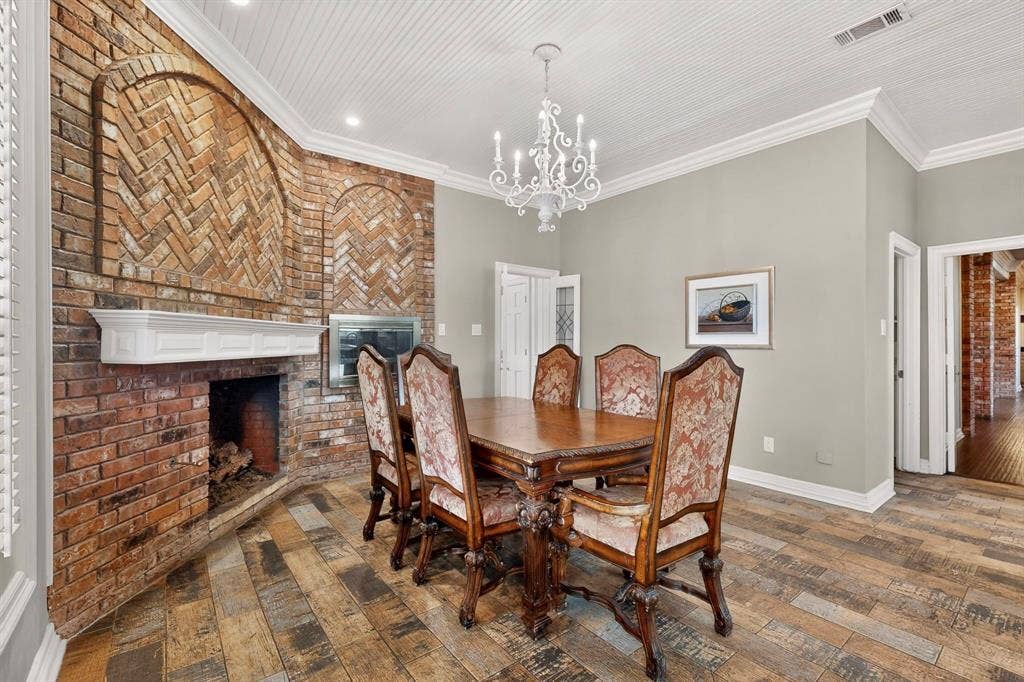 Floor-to-ceiling brick fireplace with arched herringbone inlay, wood-finish flooring, beadboard ceiling, and decorative iron chandelier