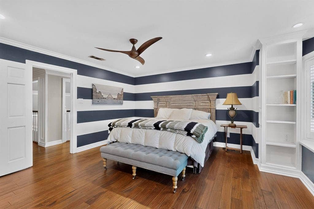 Wood-finish flooring, recessed ceiling lighting, three-blade ceiling fan, and built-in white shelving
