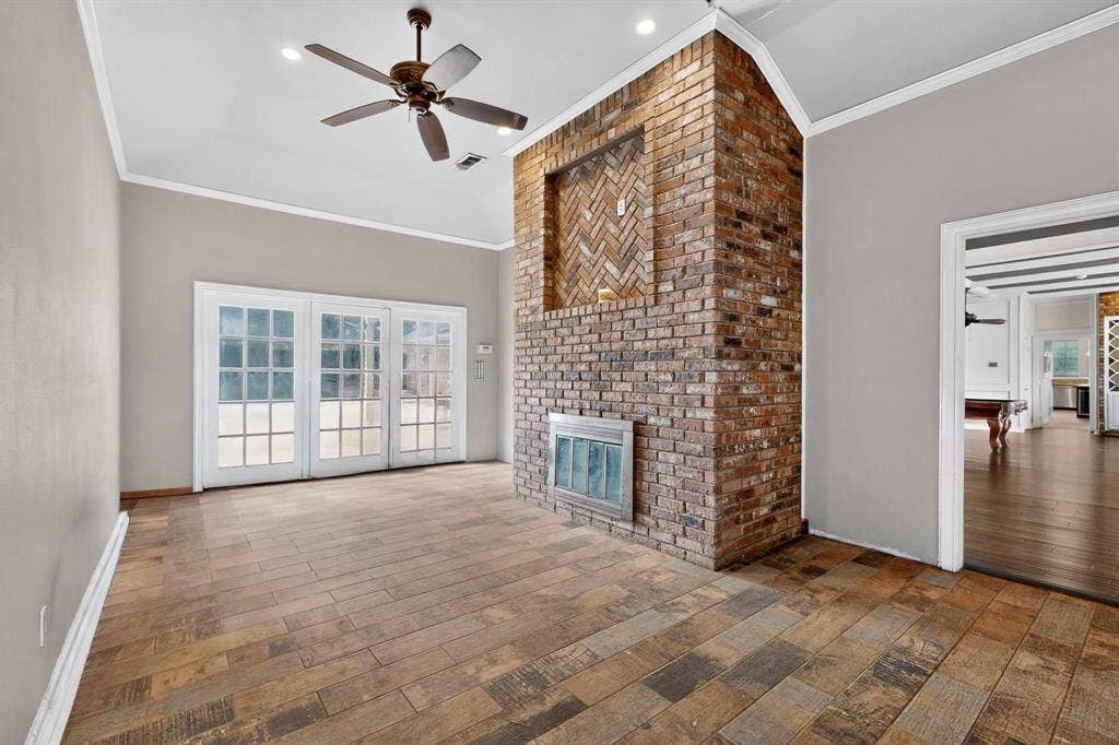 Vaulted ceilings with recessed lighting, floor-to-ceiling brick fireplace featuring a herringbone-patterned hearth, wood-finish flooring, and multi-pane glass patio doors