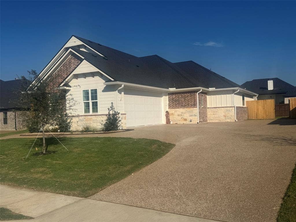10209 Charmwood Drive, Waco, TX 76712 Exterior featuring a dark shingle roof, mixed material facade with brick and stone accents, light-colored siding, an attached garage, and a concrete driveway