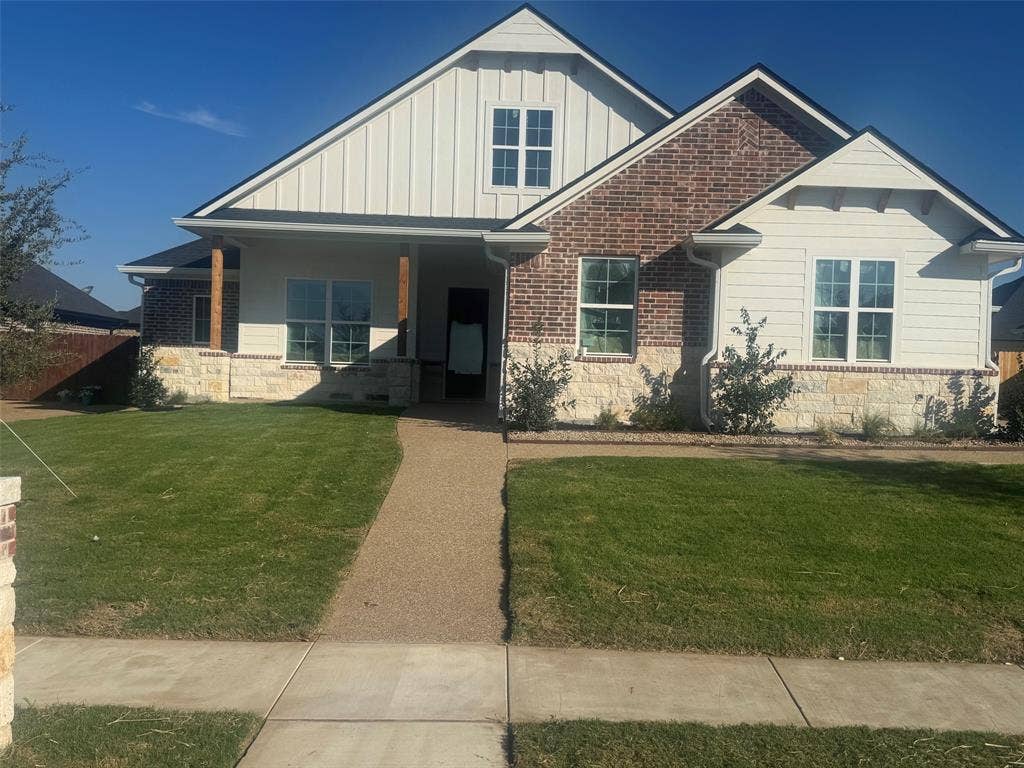 10209 Charmwood Drive, Waco, TX 76712 Exterior featuring a blend of brick and stone, vertical siding accents, a covered entry, and a gravel pathway