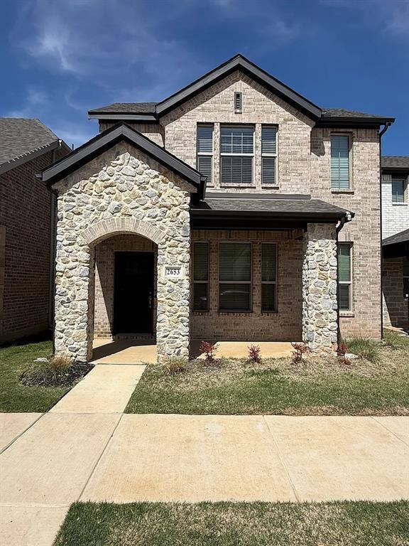 Two-story residence featuring a brick and stone facade