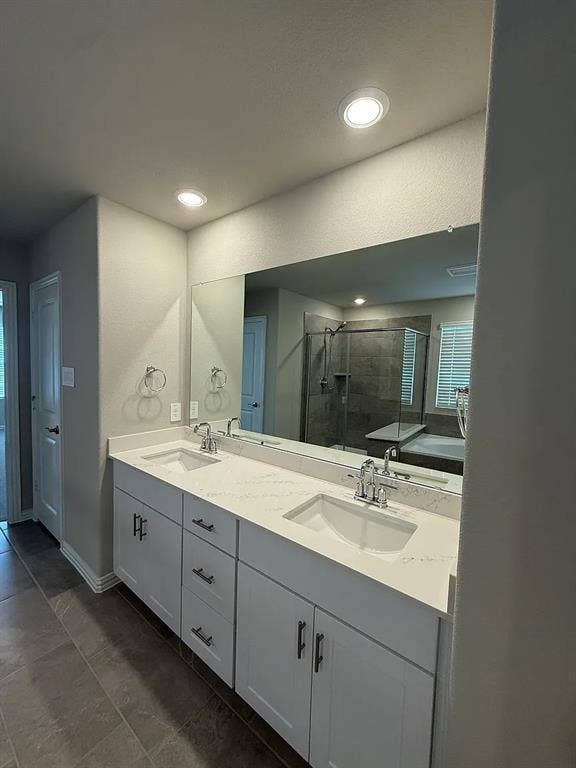 Double vanity with white cabinetry, integrated sinks, and polished chrome hardware, featuring a large wall-mounted mirror and recessed lighting
