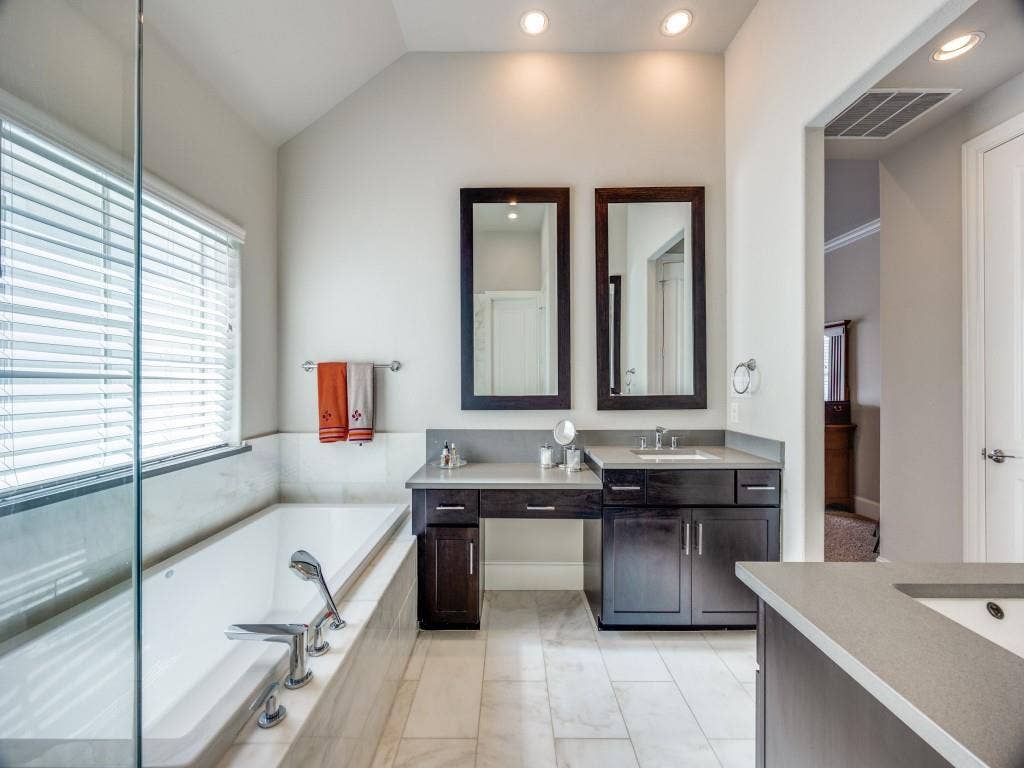 Dual dark wood vanities with integrated sinks, light-toned stone countertops, and recessed lighting