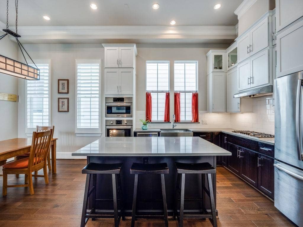 Kitchen featuring an island with countertop, stainless steel appliances, wood-finish flooring, white cabinetry, and recessed lighting