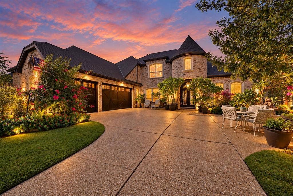Luxury takes center stage at twilight, highlighting the home’s impressive architecture, generous parking, and statement-making glass garage doors.