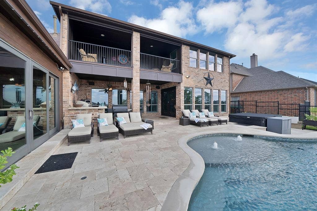 The rear of the home showcases an exceptional outdoor living experience, featuring a covered outdoor kitchen and an expansive enclosed atrium, all thoughtfully designed to embrace the beauty of the surrounding outdoor oasis.