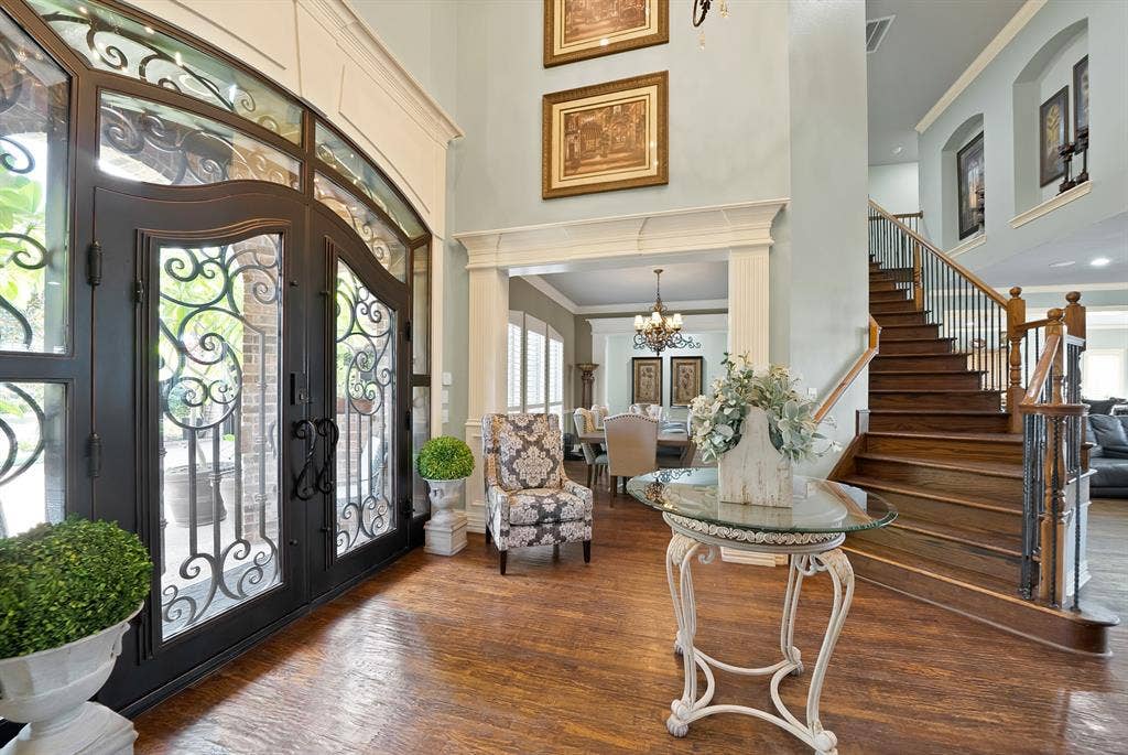 Grand and inviting foyer makes a stunning first impression, featuring beautifully crafted decorative doors that sets the tone for the exceptional elegance found throughout the home.