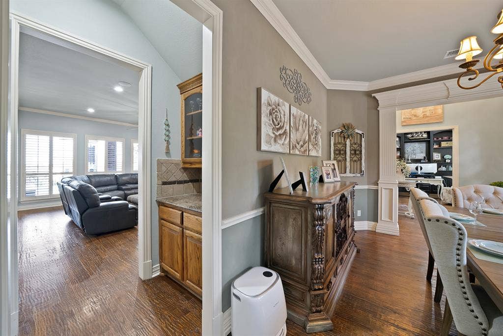 The wine or coffee bar is thoughtfully positioned directly off of kitchen and between the formal dining room and living area, offering effortless functionality for entertaining.