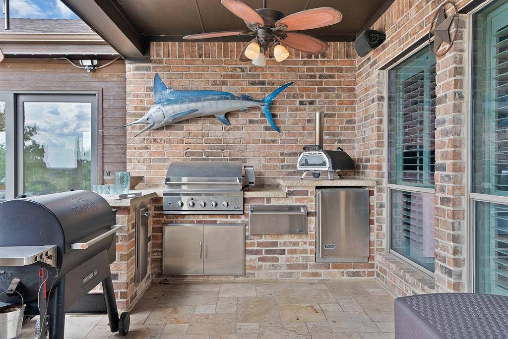 An exceptional covered outdoor kitchen elevates the art of entertaining, featuring a built-in grill, refrigerator, bun warmer, and ample space for effortless al fresco dining and gatherings.