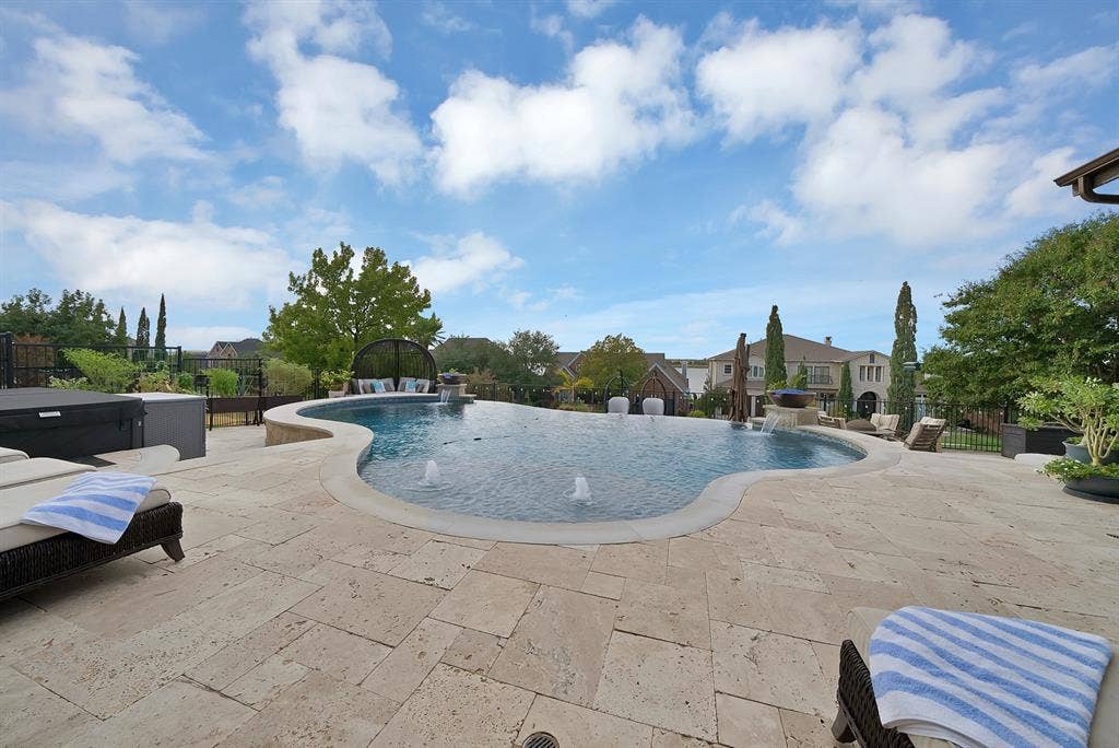 A stunning infinity-edge pool takes center stage, accented by elegant fire bowls that create a captivating ambiance. Expansive surrounding space provides plenty of room to relax, entertain, and customize your own private resort-style retreat
