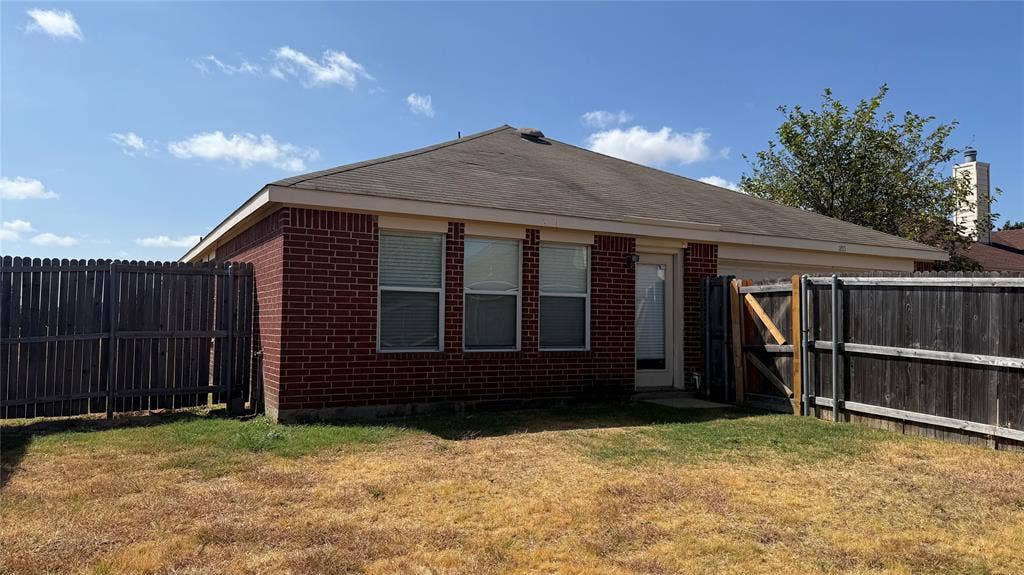 1815 Shanna Drive, Lancaster, TX 75134 Brick exterior with a partial fenced yard and a single entry door