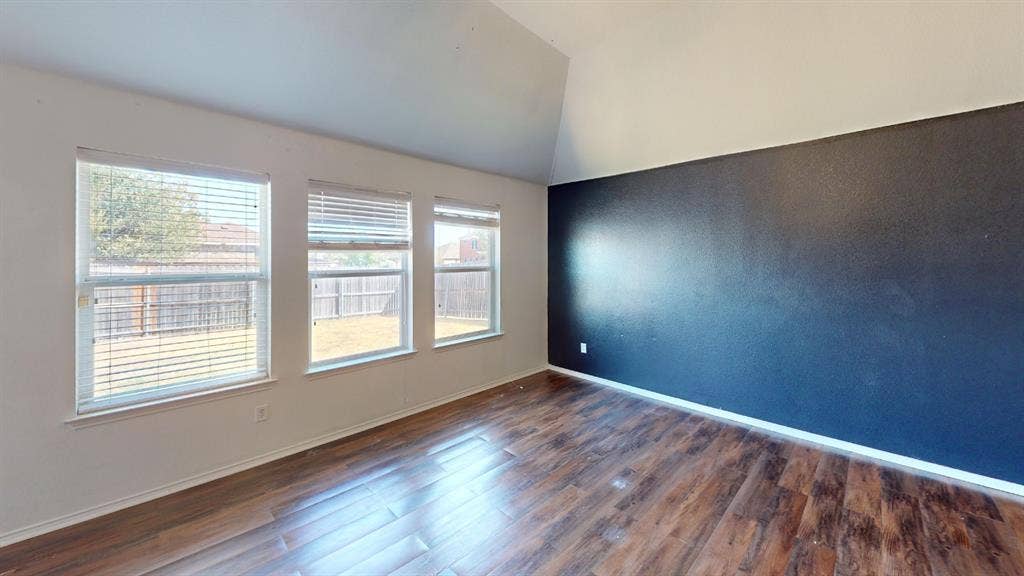 1815 Shanna Drive, Lancaster, TX 75134 Wood-finish flooring with a dark accent wall and three windows