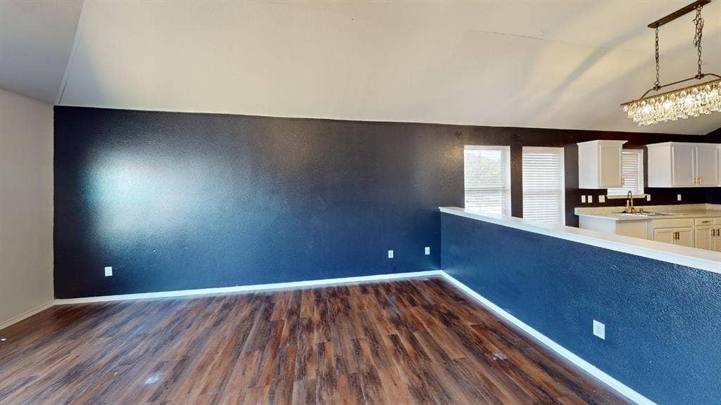 1815 Shanna Drive, Lancaster, TX 75134 Wood-finish flooring, vaulted ceilings, kitchen with white cabinetry, light-toned countertops, and a crystal chandelier