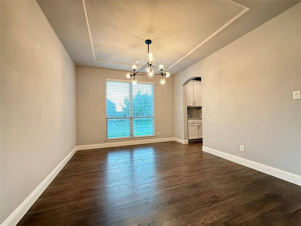 11818 Antler Drive, Frisco, TX 75035 Tray ceiling with a contemporary chandelier, wood-finish flooring, and arched doorway