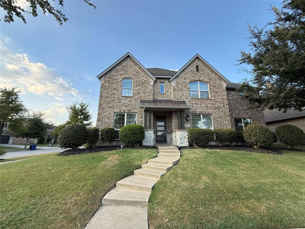 11818 Antler Drive, Frisco, TX 75035 Brick facade with stone accents, a landscaped front yard, a meandering concrete pathway, and mature shrubbery