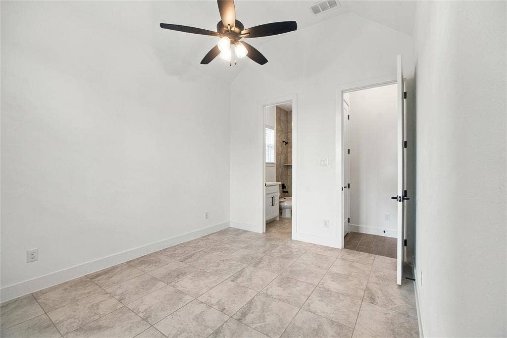 Vaulted ceiling, ceiling fan with integrated lighting, tiled flooring, white walls, and a white door with black hardware