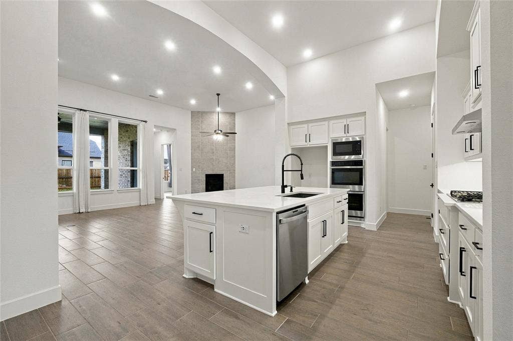 Kitchen island with integrated sink, stainless steel dishwasher, and built-in microwave and oven
