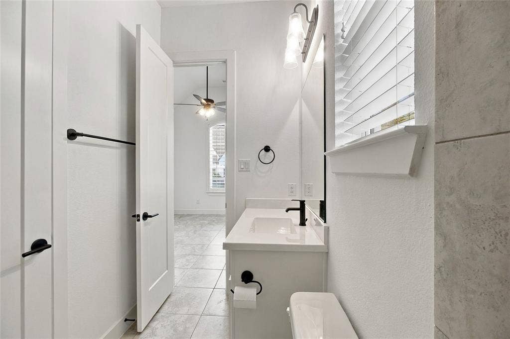 Full bathroom ensuite third bedroom featuring a single vanity with a white countertop, matte black faucet