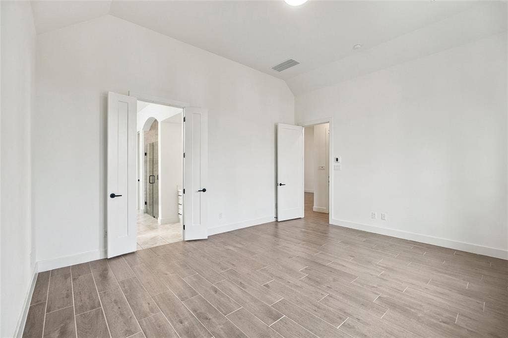 1st primary bedroom 14x17 featuring vaulted ceiling, wood-finish flooring