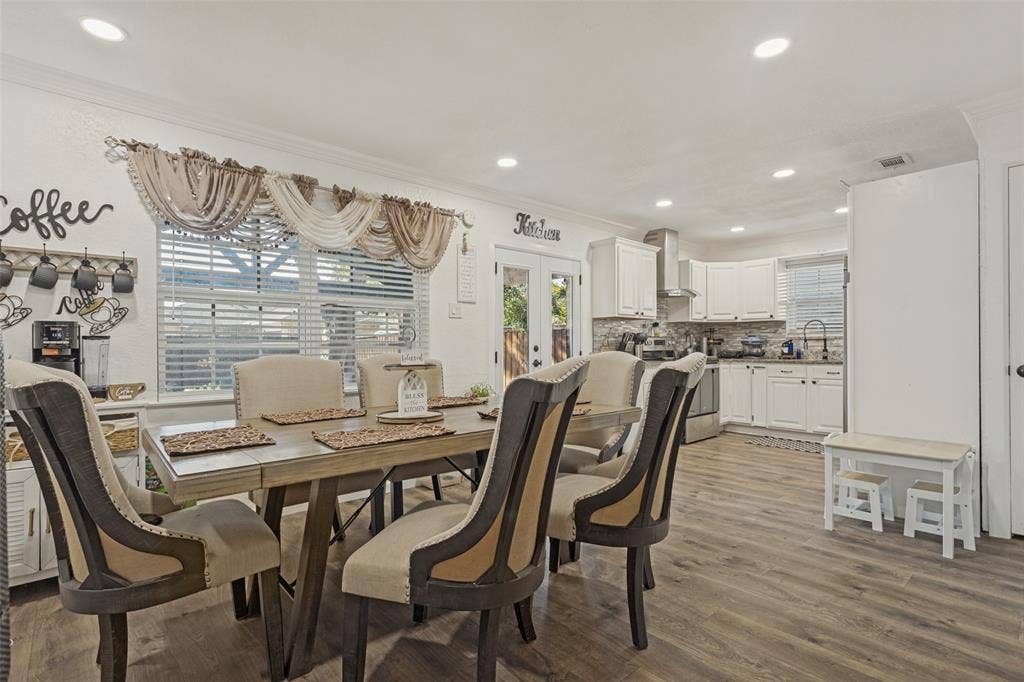 1522 Carroll Drive, Garland, TX 75041 Open-concept area featuring wood-finish flooring, recessed lighting, white cabinetry, a built-in kitchen range hood, and glass-paneled double doors