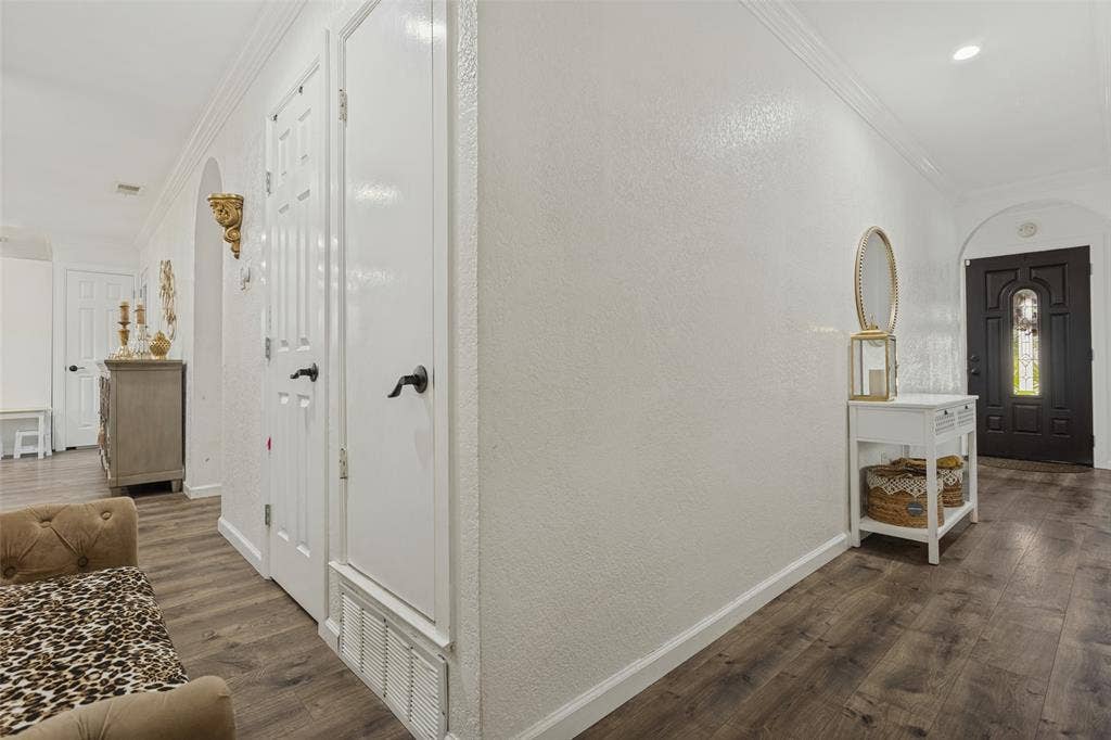 1522 Carroll Drive, Garland, TX 75041 Entryway featuring dark-stained wood-finish flooring, white paneled doors with matte black hardware, arched wall openings, and a dark-finished exterior entry door with an integrated glass panel