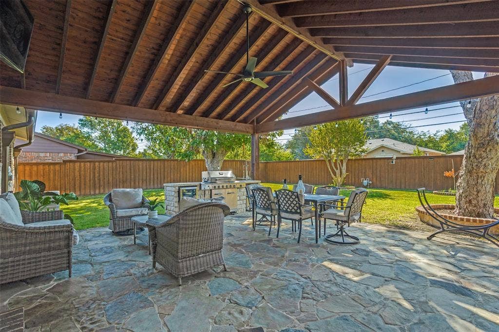 1522 Carroll Drive, Garland, TX 75041 Covered outdoor living space featuring a timber-framed vaulted ceiling, flagstone patio, built-in masonry grill station, and integrated ceiling fan