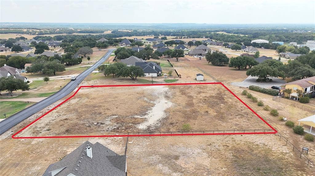 157 Helton Drive, Granbury, TX 76049 Expansive undeveloped lot featuring a paved road frontage and perimeter fencing on three sides