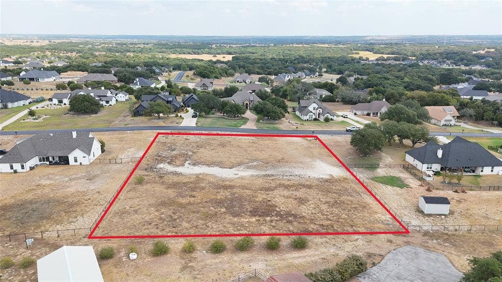 157 Helton Drive, Granbury, TX 76049 Expansive lot with surrounding residential properties, clear land, and distant tree line