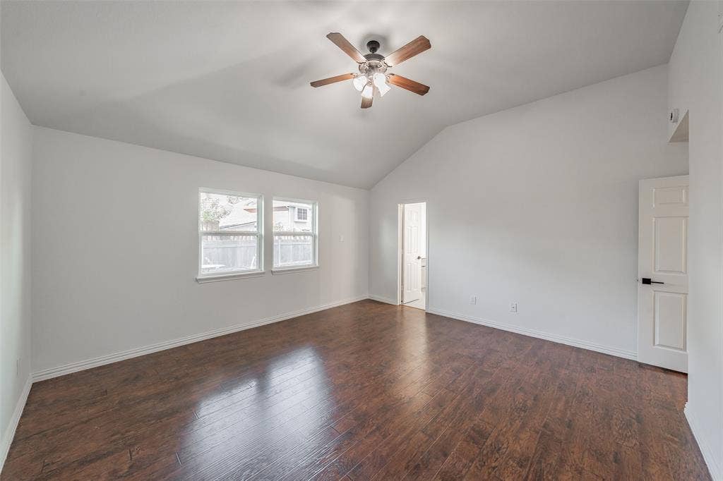617 Dover Court, Coppell, TX 75019 First floor primary bedroom has vaulted ceiling with a ceiling fan, wood flooring, and large windows and white interior walls
