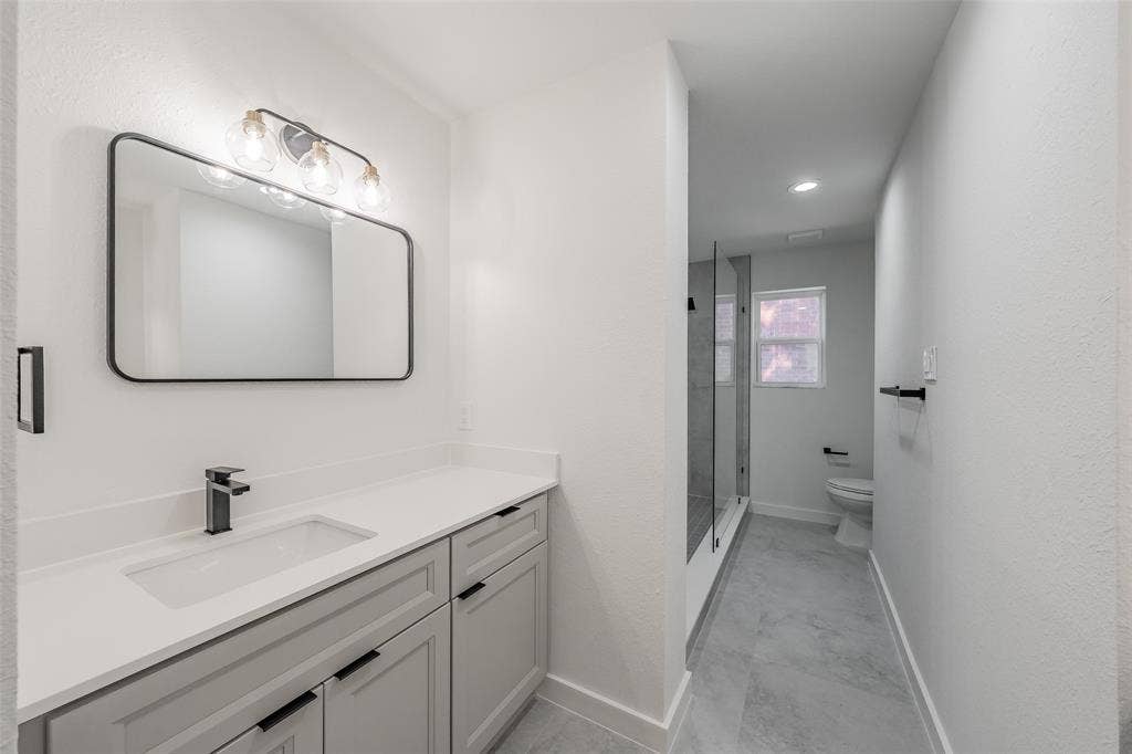 617 Dover Court, Coppell, TX 75019 Second vanity with an integrated rectangular sink, matte black faucet, and light gray cabinetry leads to oversized shower and private toilet area